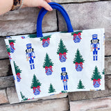 White rectangular market tote with nutcracker print and blue handles.