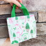 Small tote bag with Christmas-themed design featuring trees, wreaths, and presents on a white background.