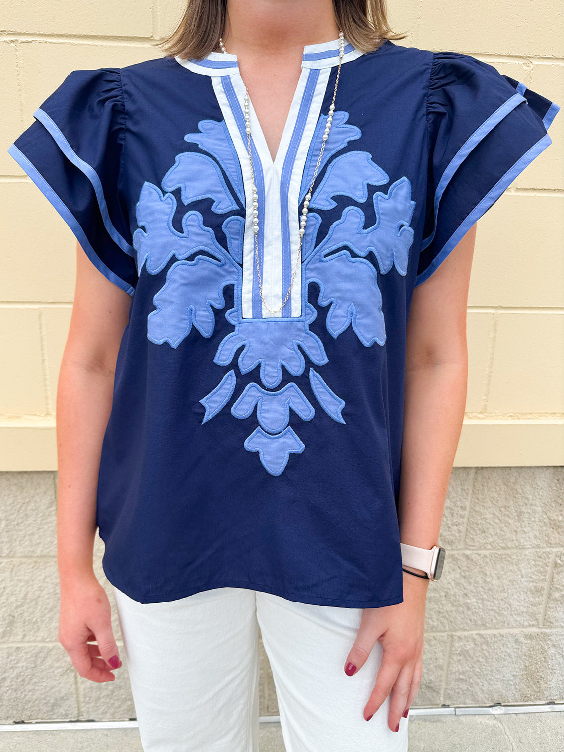 Navy embroidered flutter sleeve top with multicolor appliqué and V-neckline—lightweight and versatile for everyday wear