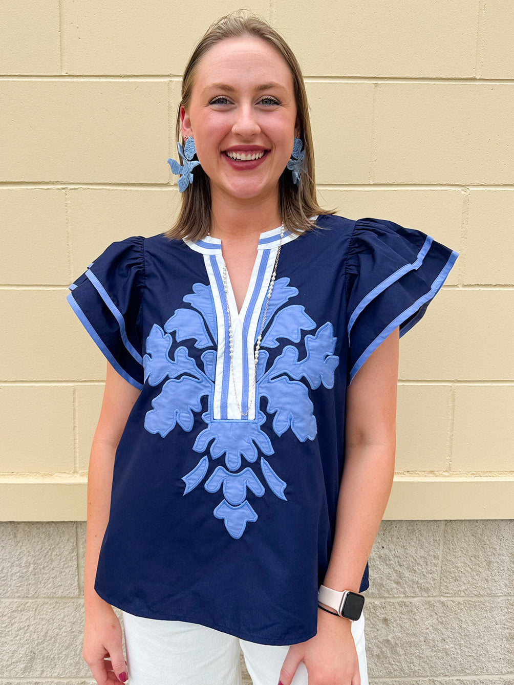 Navy embroidered flutter sleeve top with multicolor appliqué and V-neckline—lightweight and versatile for everyday wear