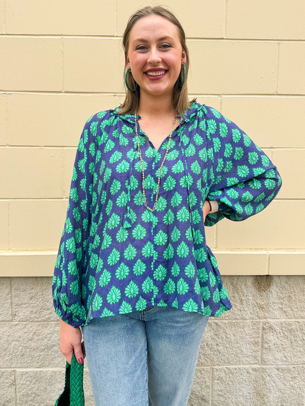 Flowy navy and green patterned blouse with tie-neck, ruffle collar, dolman sleeves, and elastic cuffs—lightweight and oversized