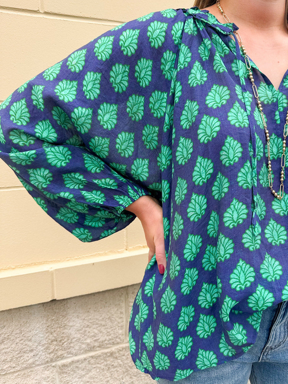 Flowy navy and green patterned blouse with tie-neck, ruffle collar, dolman sleeves, and elastic cuffs—lightweight and oversized
