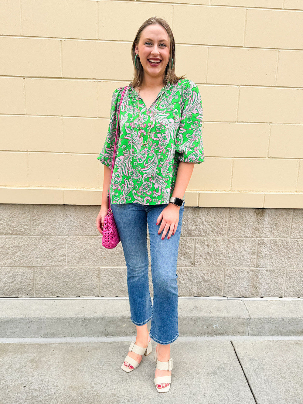 Green and pink paisley print blouse with frilled tie neckline and three-quarter peasant sleeves displayed on hanger against a neutral background