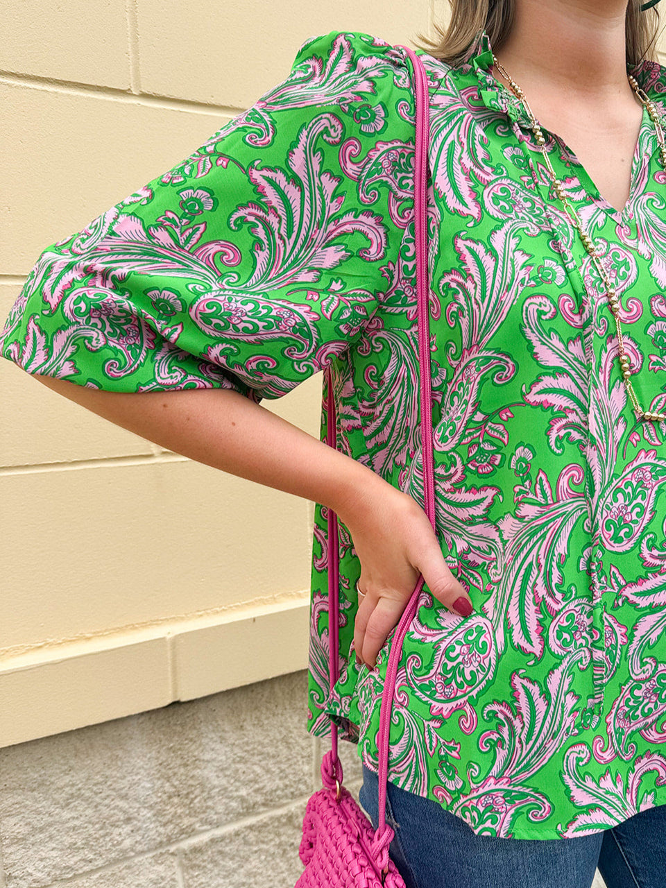 Green and pink paisley print blouse with frilled tie neckline and three-quarter peasant sleeves displayed on hanger against a neutral background