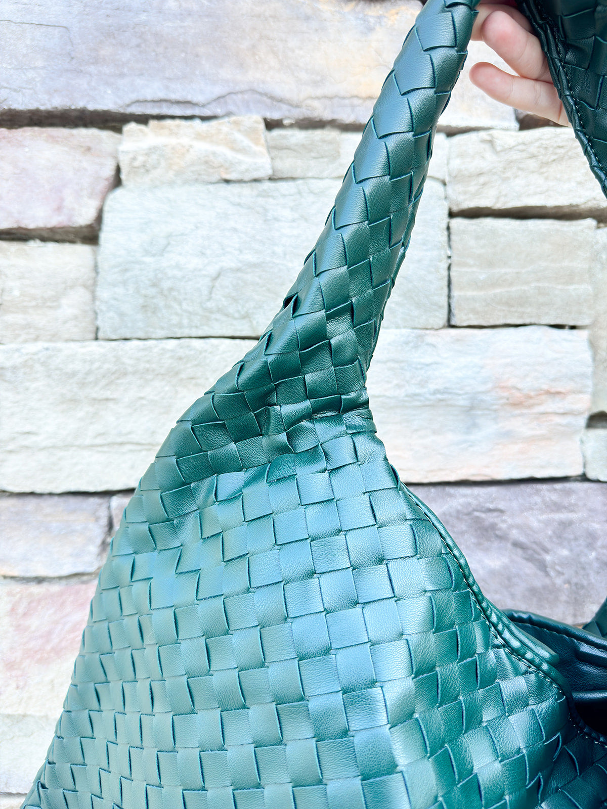 Green woven shoulder bag with soft structure and magnetic closure, designed for stylish and functional everyday use
