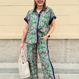 Floral paisley button-down blouse with navy collar, pink trim, high-low hem, and navy-trimmed sleeves—lightweight and chic