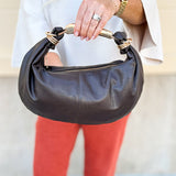 Chocolate brown asymmetrical pleather handbag with gold handle, gold hardware, and detachable crossbody strap.