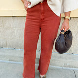 Rust acid-washed high-waisted bootcut pants with frayed hem.