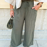 Olive wide-leg linen pants with drawstring waist, cropped length, and frayed hem.