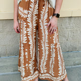 Clay and cream wide-leg pants with elastic waistband, pleating details, and side pockets.