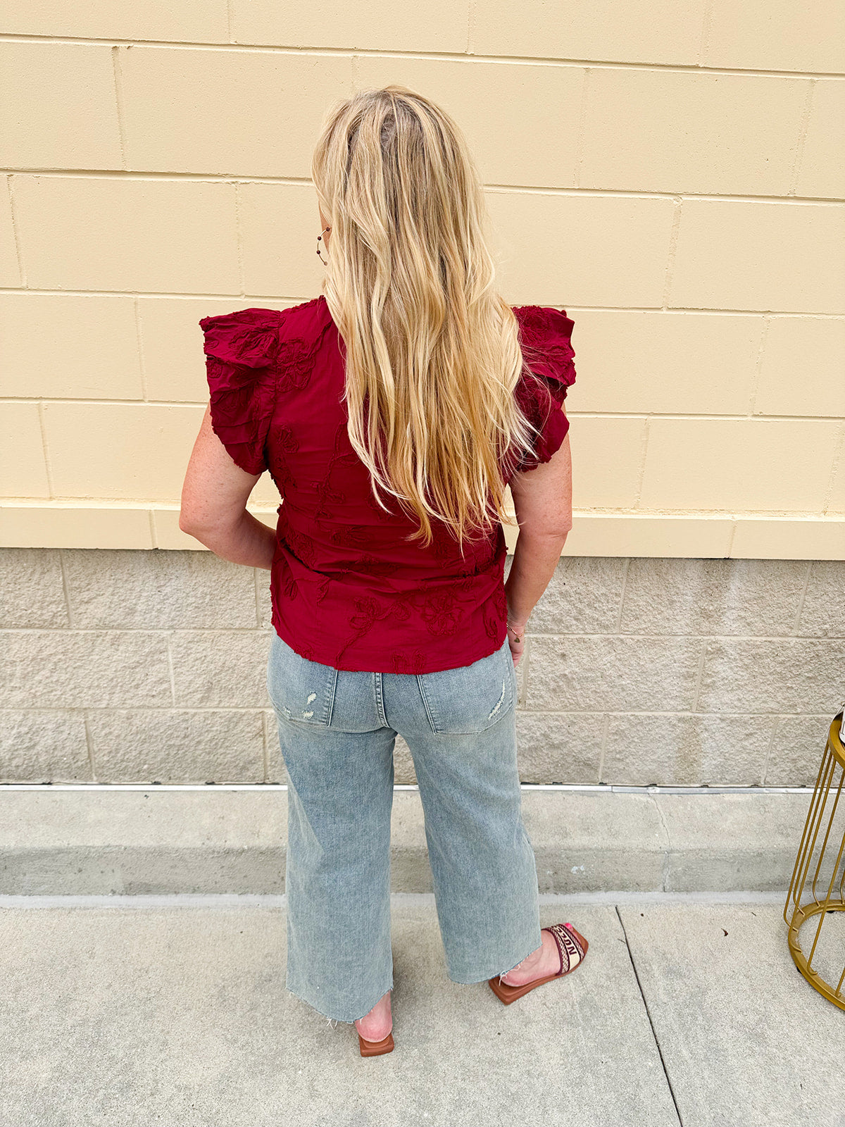 Model wearing light wash, cropped wide leg jeans with raw hem and light distressing. Jeans feature a mid-rise waist and tummy control panel.