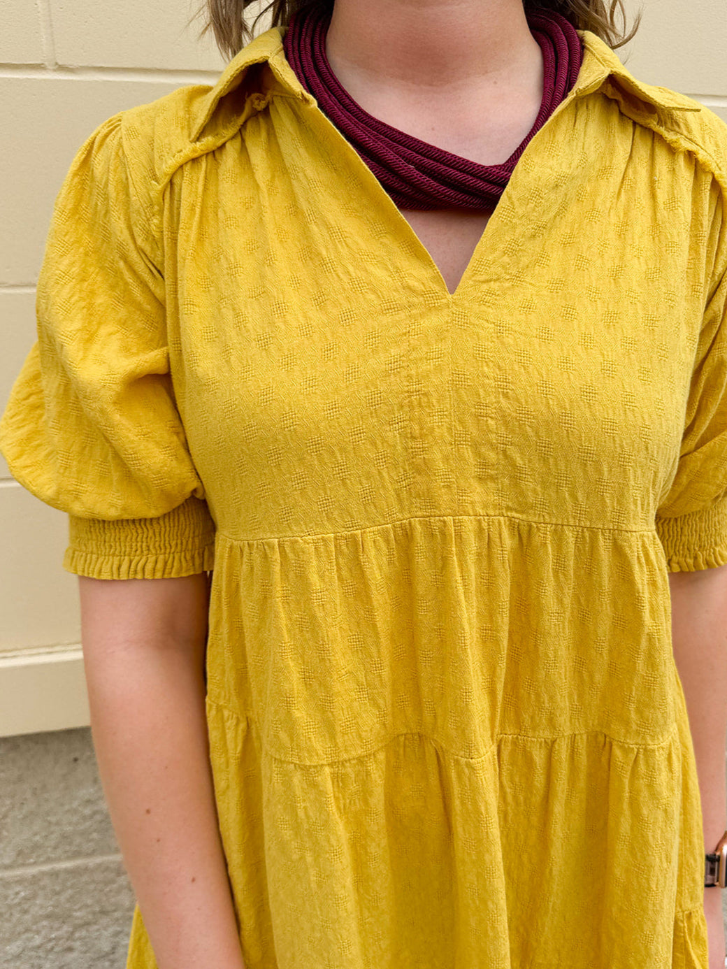 Mustard cotton mini dress with a collar, tiered A-line shape, and smocked cuff balloon sleeves—perfect for gameday style.