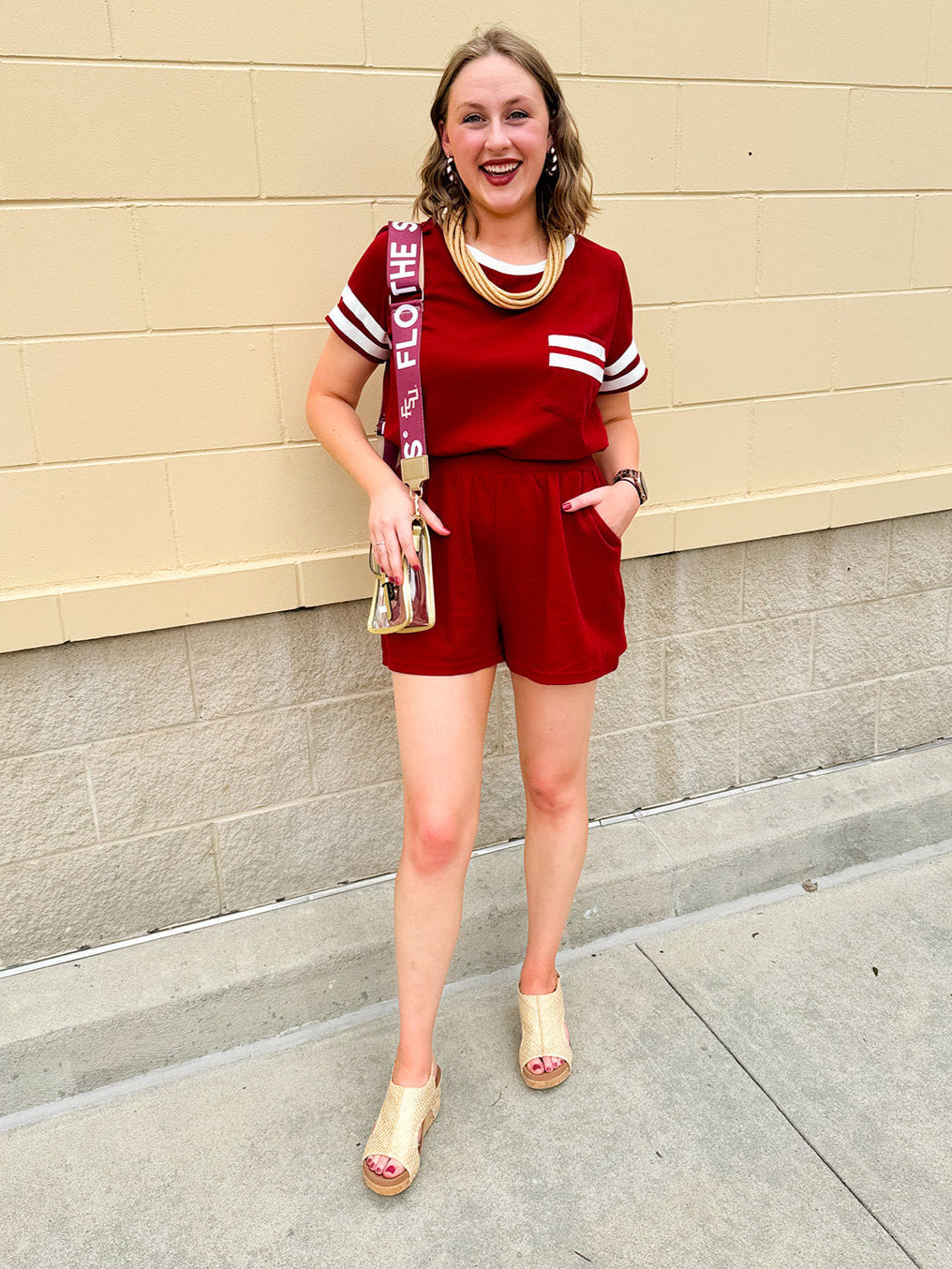 Garnet knit romper with white contrast trim on neckline, sleeves, and chest pocket. Features half sleeves, elastic waist, and keyhole back—sporty and stylish.