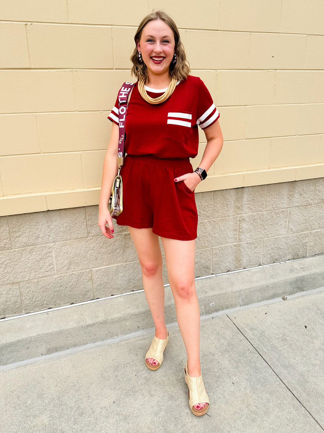 Garnet knit romper with white contrast trim on neckline, sleeves, and chest pocket. Features half sleeves, elastic waist, and keyhole back—sporty and stylish.