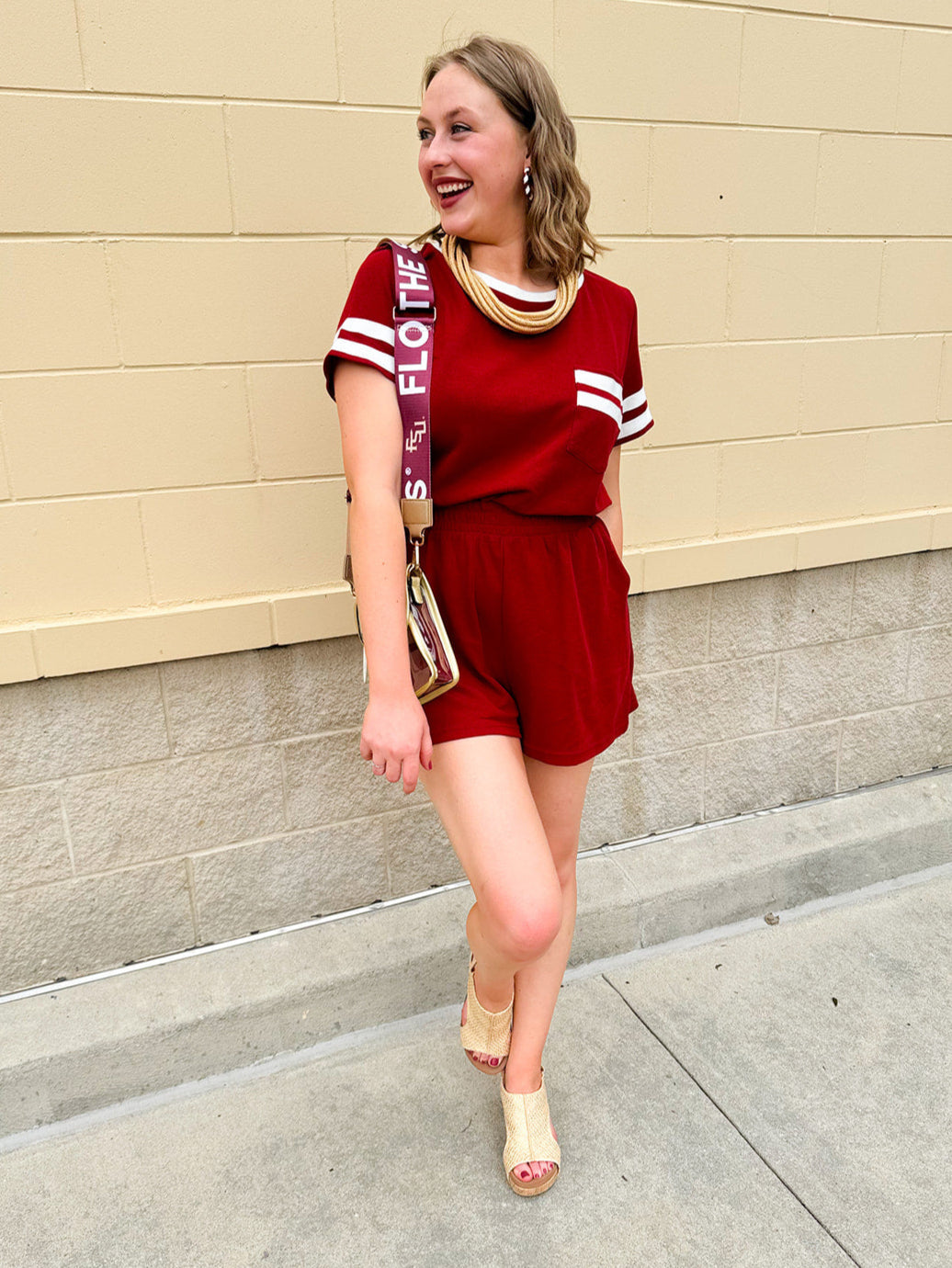 Garnet knit romper with white contrast trim on neckline, sleeves, and chest pocket. Features half sleeves, elastic waist, and keyhole back—sporty and stylish.