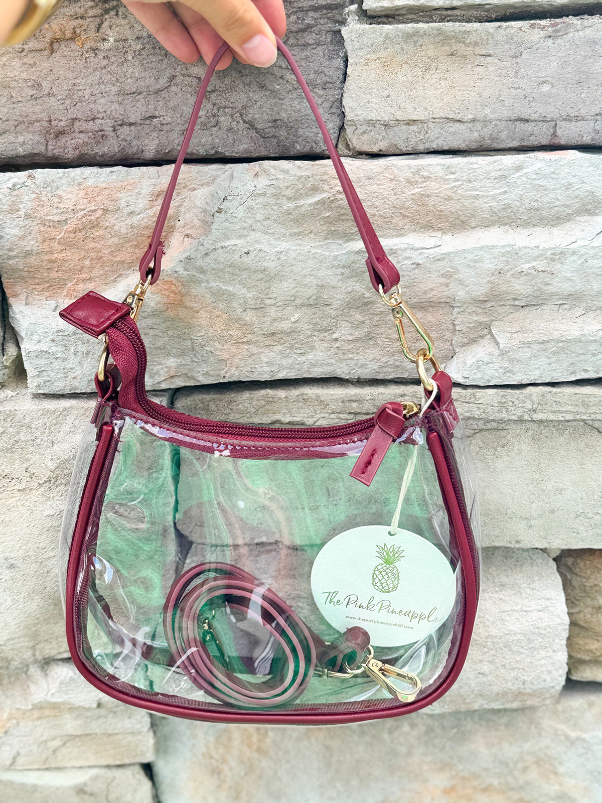 Clear crossbody stadium bag with garnet straps and gold hardware, perfect for stylish game day looks.