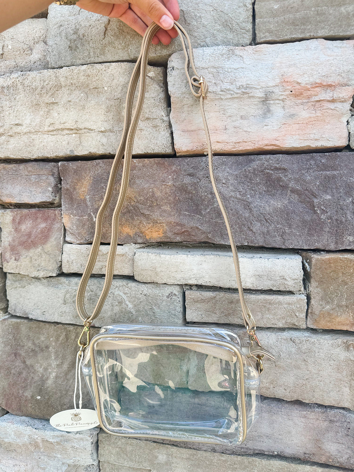 Clear crossbody purse with gold vegan leather trim and brass hardware, perfect for stadium entry and stylish events.