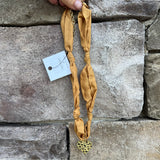 Gold scarf-style necklace with knotted details and hammered metal heart pendant.