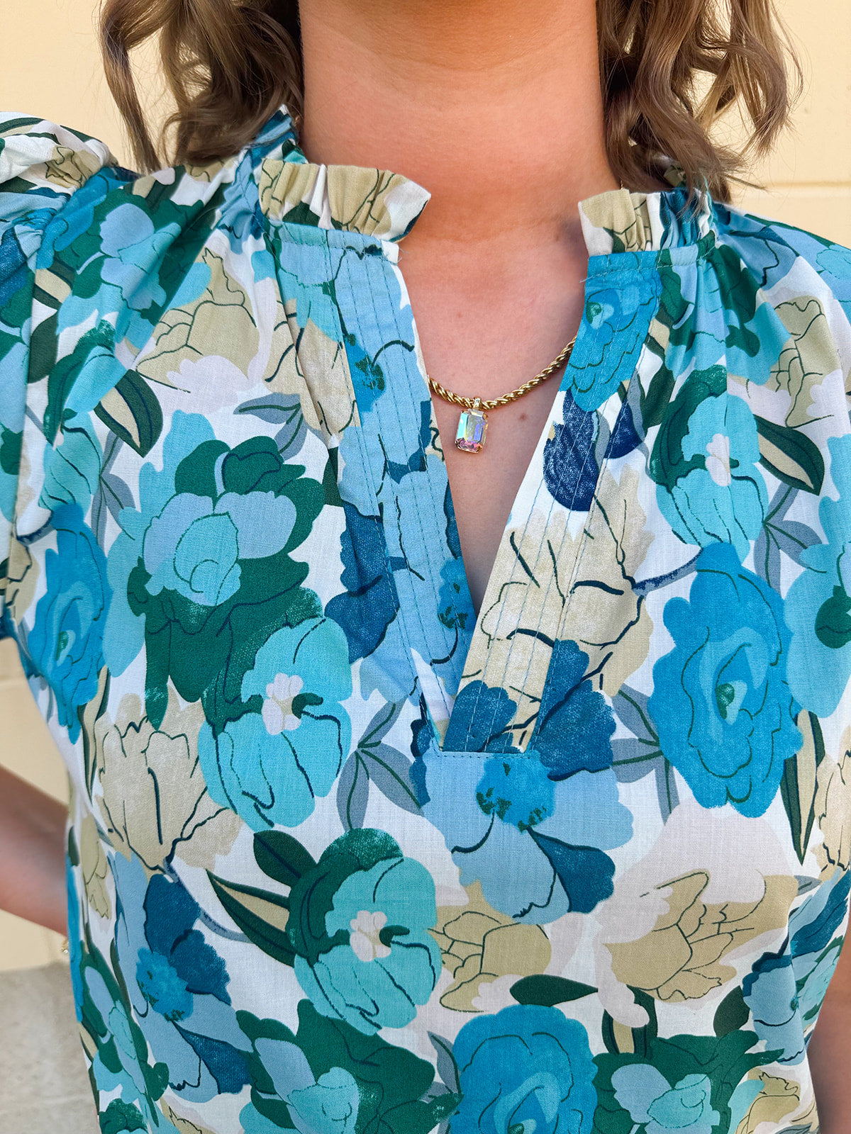 Blue floral blouse with pink accents, featuring a ruffle-trimmed split neckline and short puff sleeves