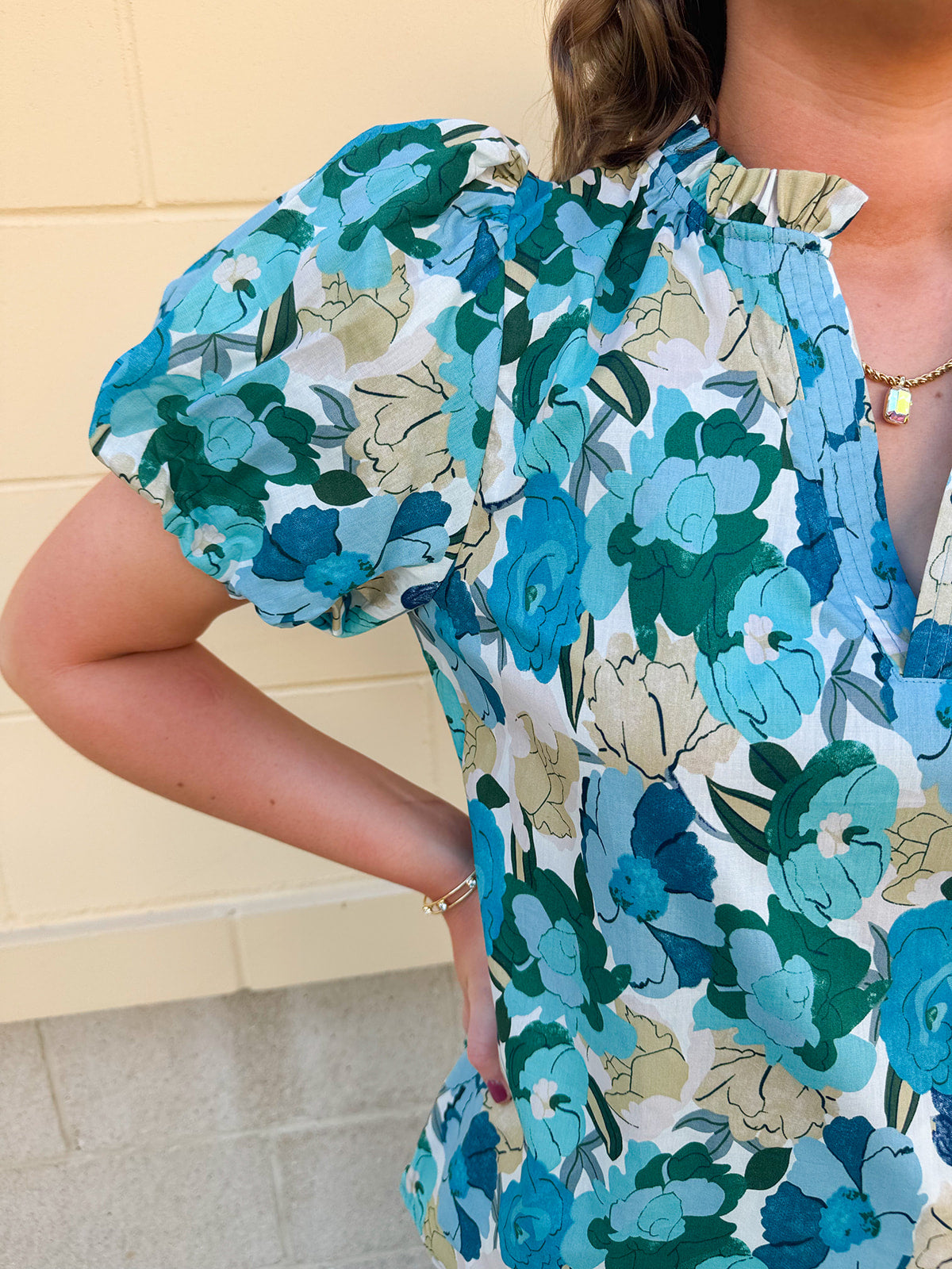 Blue floral blouse with pink accents, featuring a ruffle-trimmed split neckline and short puff sleeves