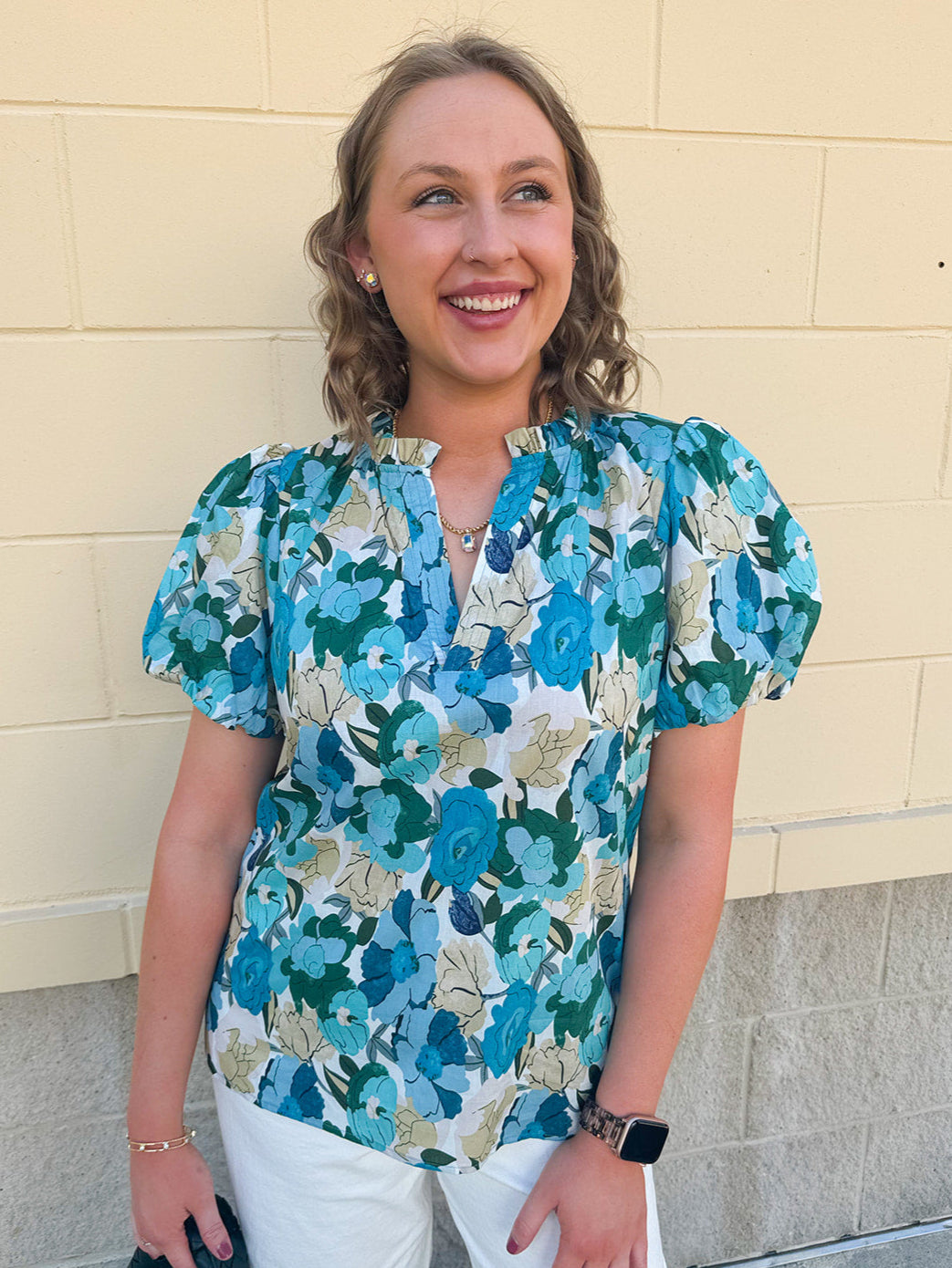 Blue floral blouse with pink accents, featuring a ruffle-trimmed split neckline and short puff sleeves