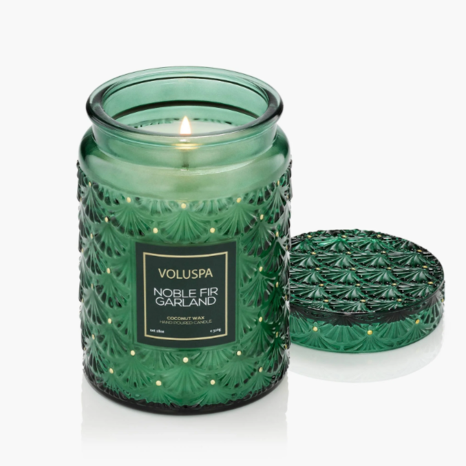 Large holiday candle in embossed glass jar with matching lid, glowing with festive detail.