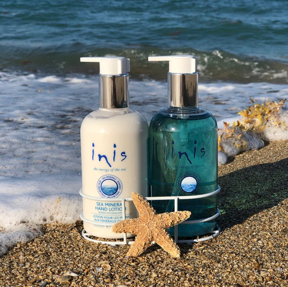 White metal caddy holding two 10 oz. bottles of Inis hand soap and hand lotion with coastal blue labels.