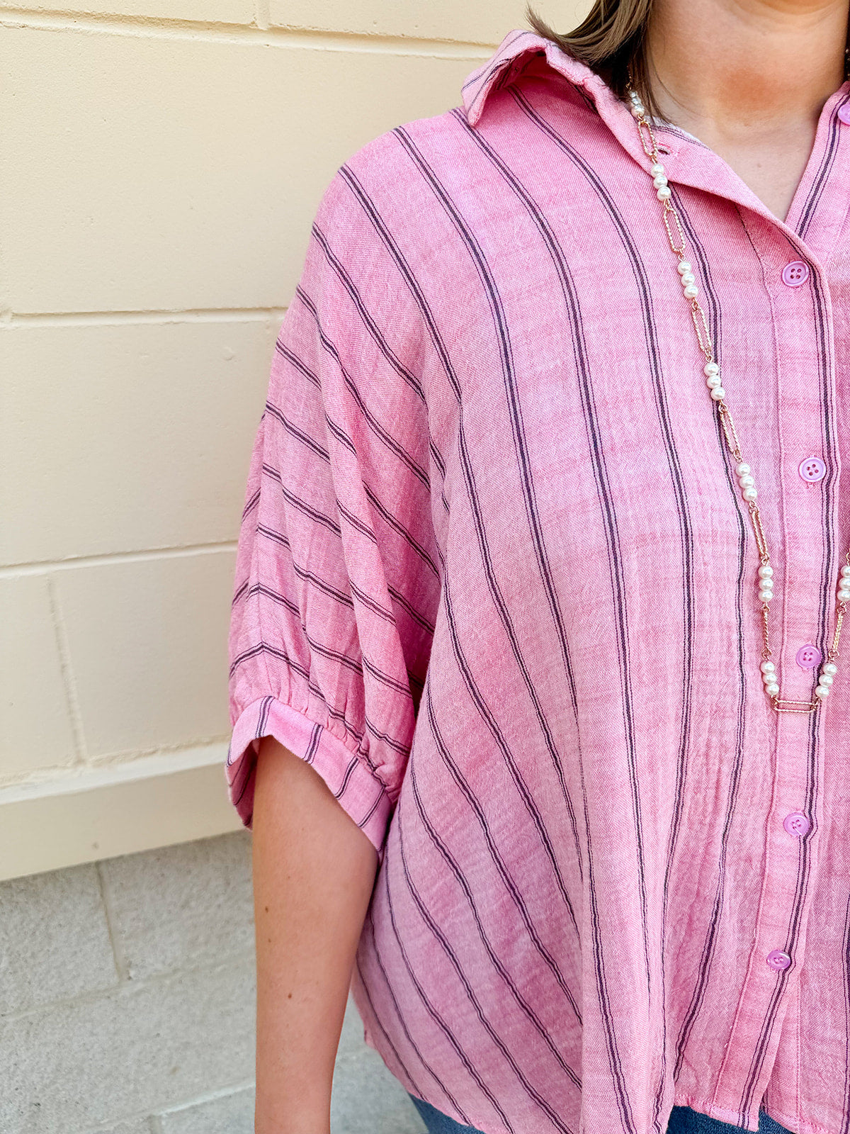 Oversized pink striped cotton gauze blouse with collar, button-down front, drop shoulders, and half sleeves.