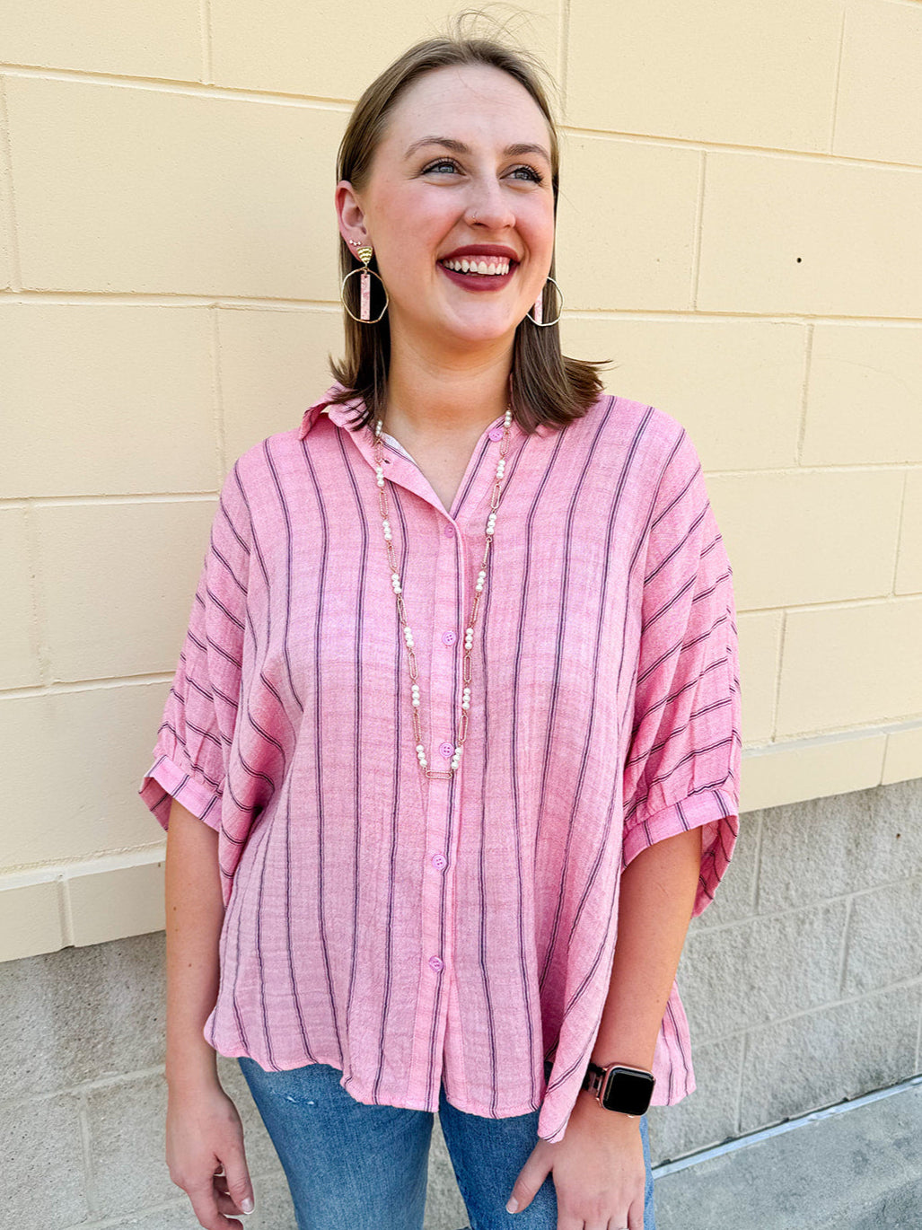 Oversized pink striped cotton gauze blouse with collar, button-down front, drop shoulders, and half sleeves.