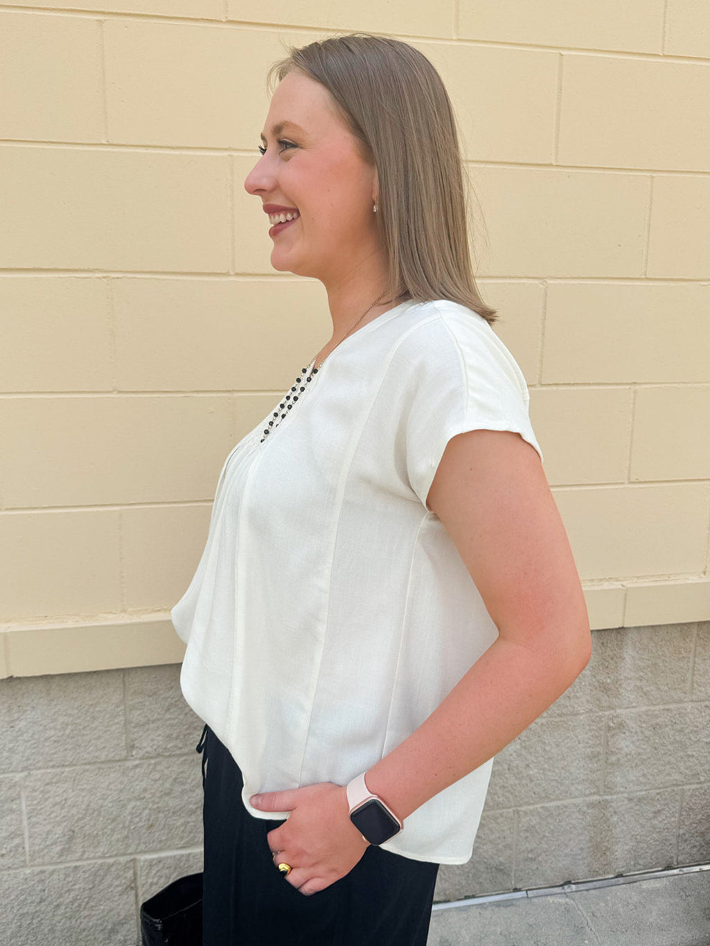 Neutral short sleeve top with smocking and pleated details, styled for a casual polished look