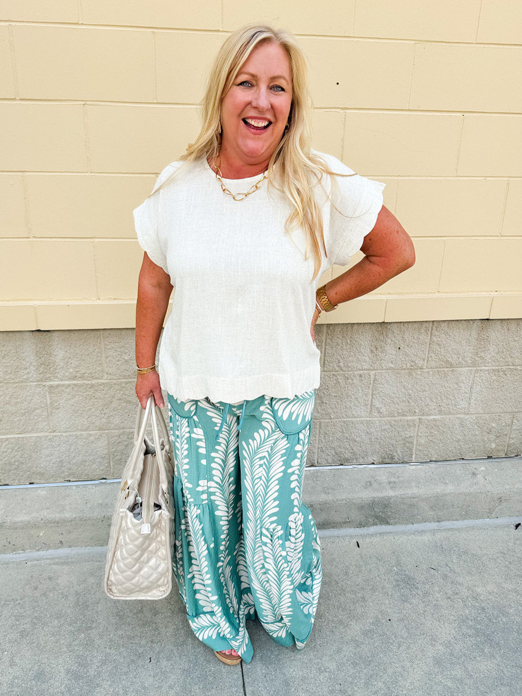 Lightweight printed wide-leg pants with a tropical pattern in dusty blue and cream tones, featuring a drawstring waist and pockets.