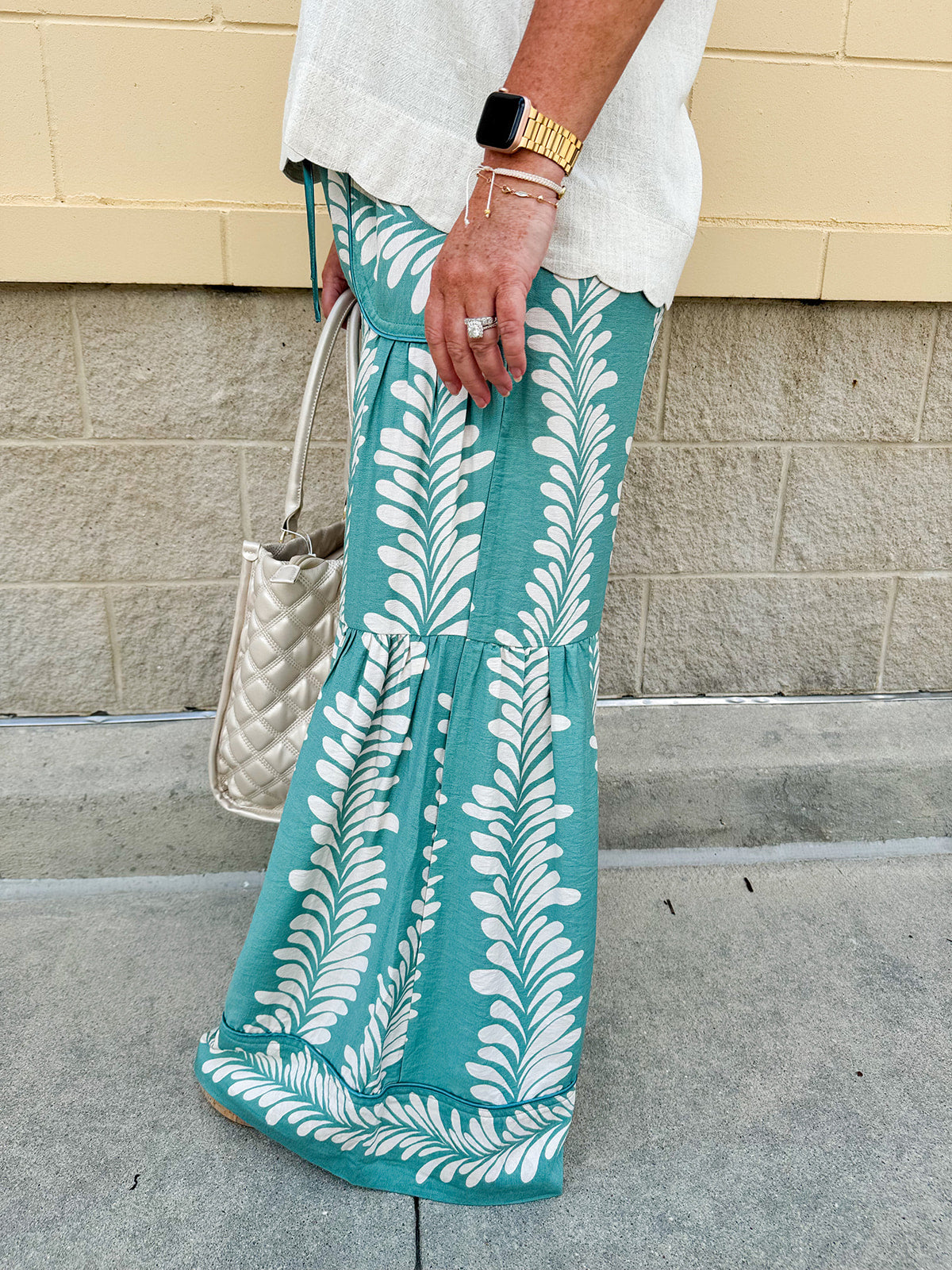 Lightweight printed wide-leg pants with a tropical pattern in dusty blue and cream tones, featuring a drawstring waist and pockets.