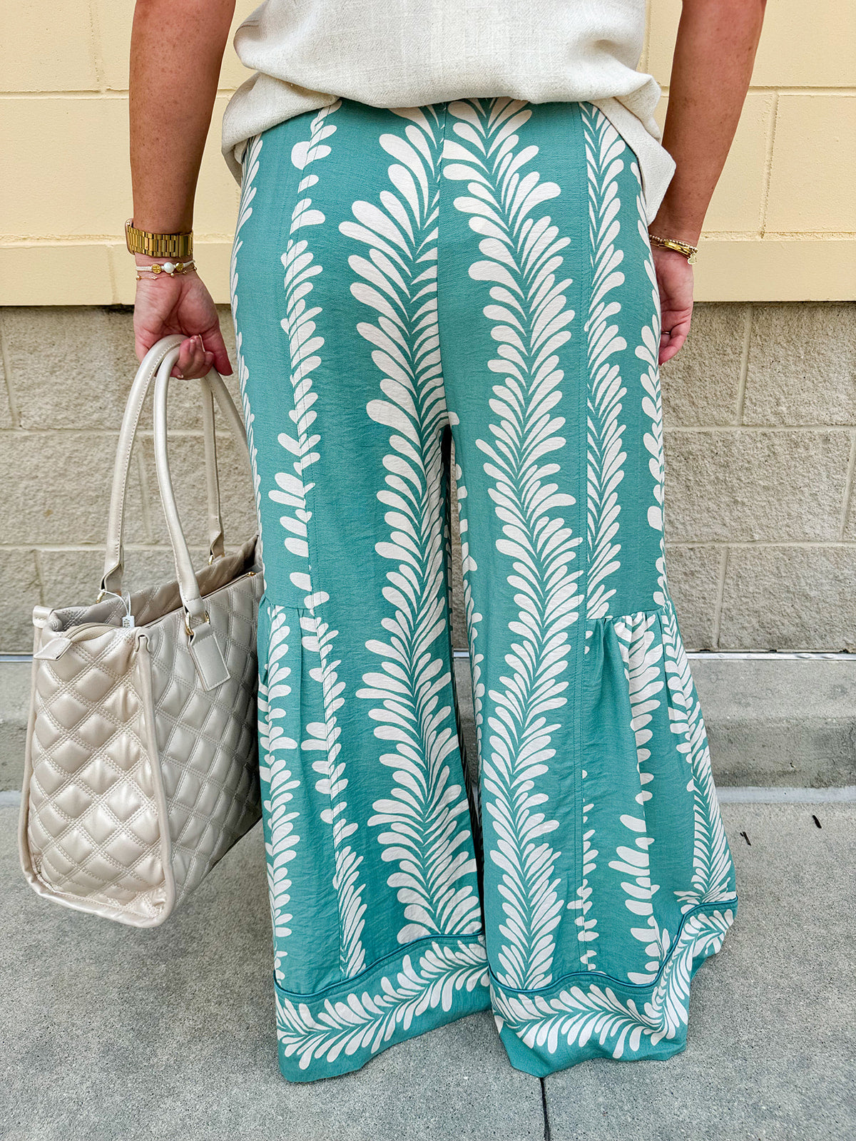 Lightweight printed wide-leg pants with a tropical pattern in dusty blue and cream tones, featuring a drawstring waist and pockets.