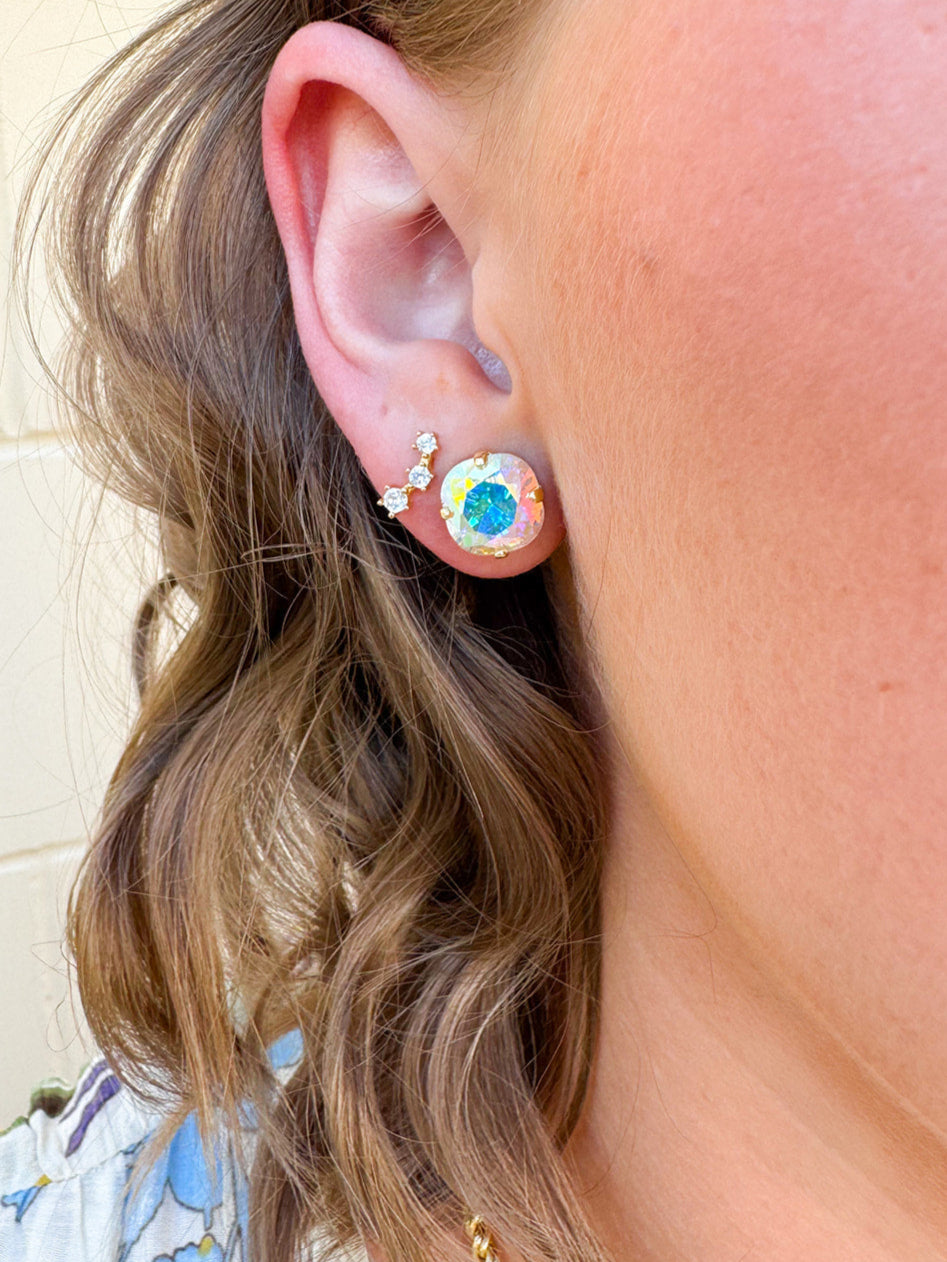 A pair of Sorrelli Halcyon Stud Earrings in Crystal Aurora Borealis, featuring a gold-colored setting and a large, multicolored, round crystal.