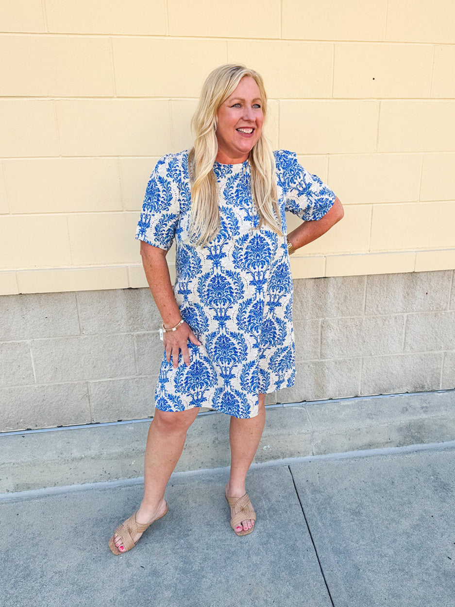 Blue and white damask print short-sleeve mini dress with pockets and back zipper closure, styled for a casual yet polished look.
