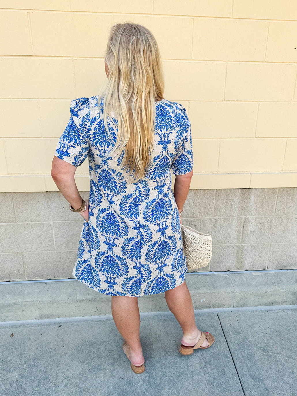 Blue and white damask print short-sleeve mini dress with pockets and back zipper closure, styled for a casual yet polished look.