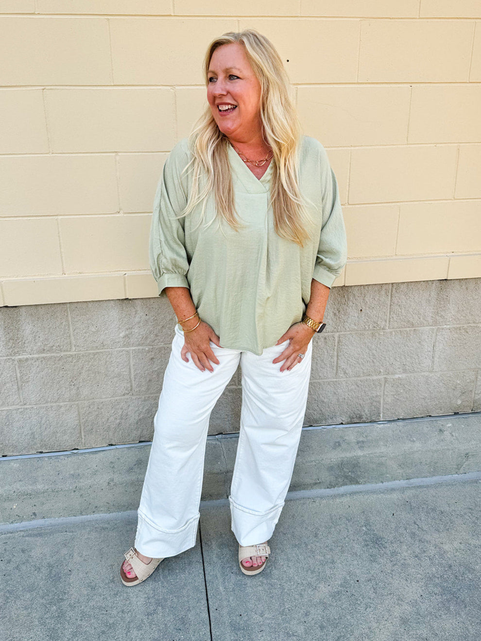 Sage green V-neck loose-fit blouse with pleated cuffed sleeves, styled for a fresh and effortless look.