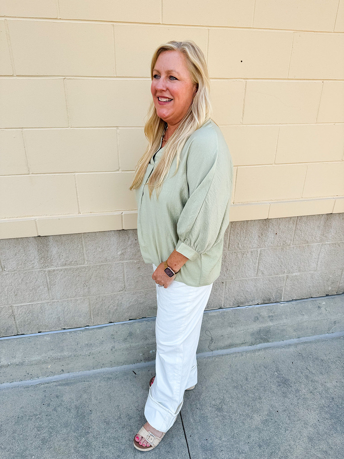 Sage green V-neck loose-fit blouse with pleated cuffed sleeves, styled for a fresh and effortless look.