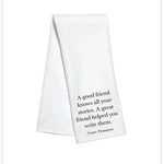 White kitchen towel with black text reading “A good friend knows all your stories. A great friend helped you write them.”