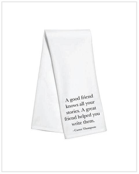 White kitchen towel with black text reading “A good friend knows all your stories. A great friend helped you write them.”