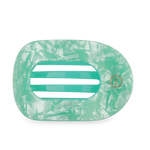 Large green flat round hair clip on a light surface