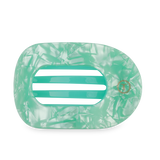 Large green flat round hair clip on a light surface