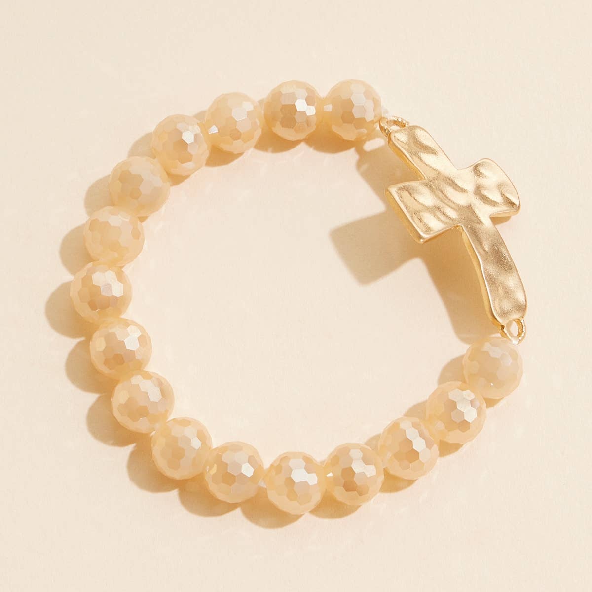 Natural light tan glass beaded stretch bracelet with hammered metal cross charm.