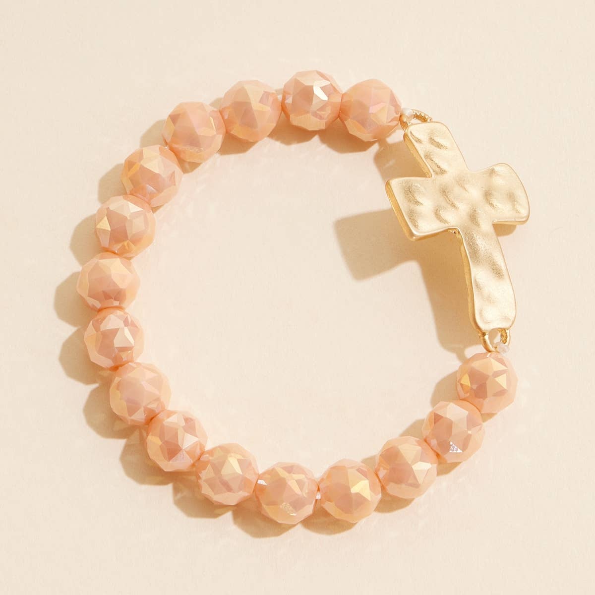 Taupe glass beaded stretch bracelet with hammered metal cross charm.