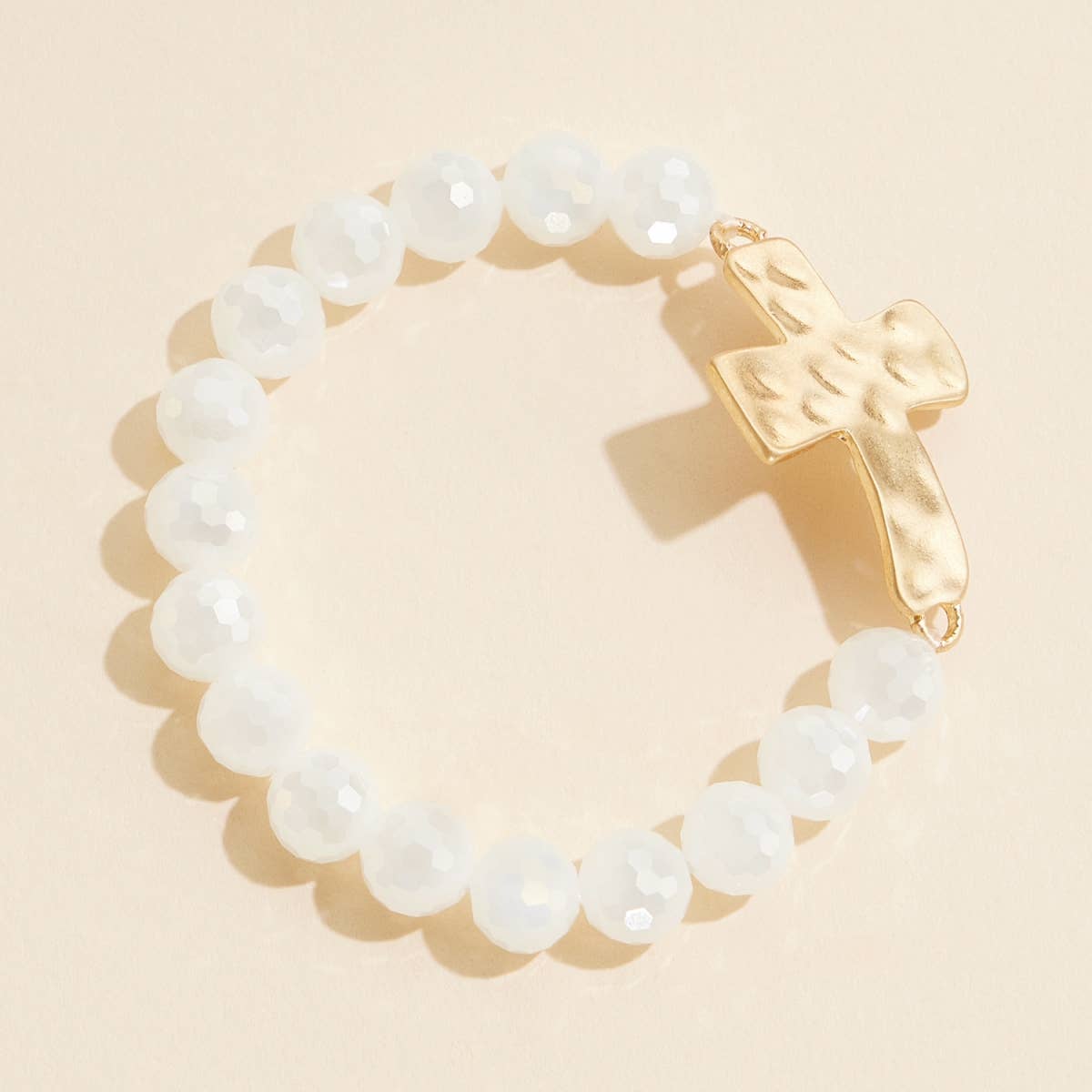 White glass beaded stretch bracelet with hammered metal cross charm.