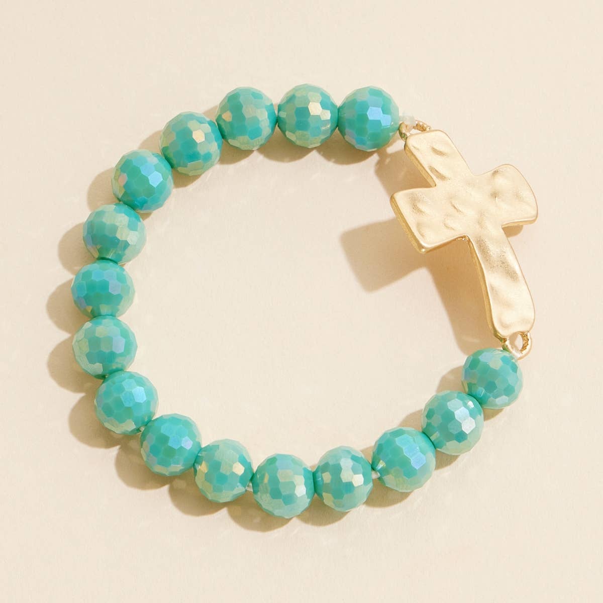 Teal glass beaded stretch bracelet with hammered metal cross charm.