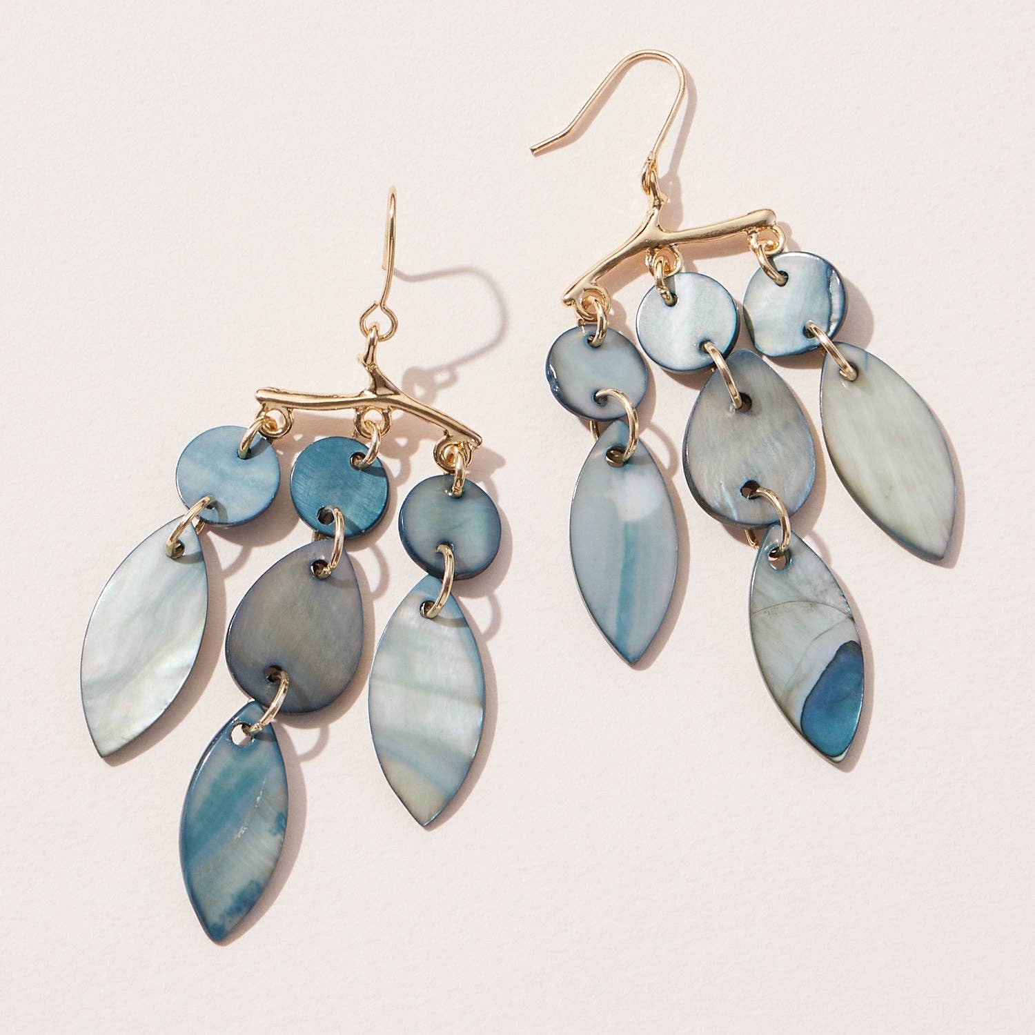 A pair of dangling mobile art shell earrings with various shades of blue and gold tones.