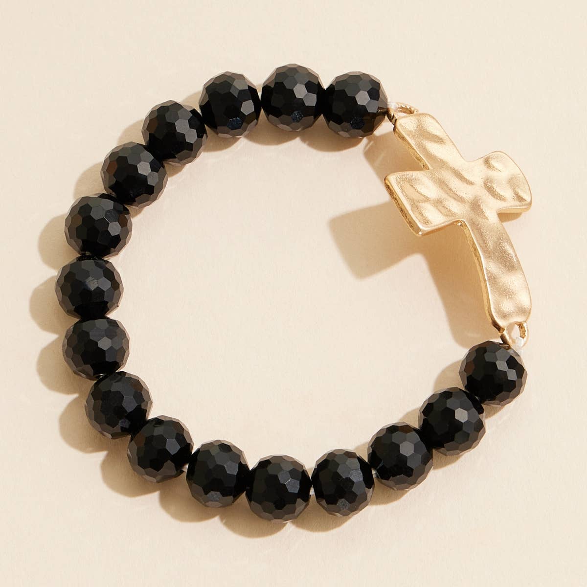 Black glass beaded stretch bracelet featuring a hammered metal cross charm.