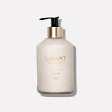 Elegant glass bottle of L'AVANT Blushed Bergamot Hand Lotion with brushed gold pump and moisturizing plant-based formula.
