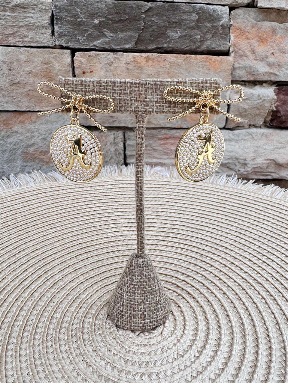 Gold bow earrings with pearl-accented medallion drops featuring the Alabama Script "A."